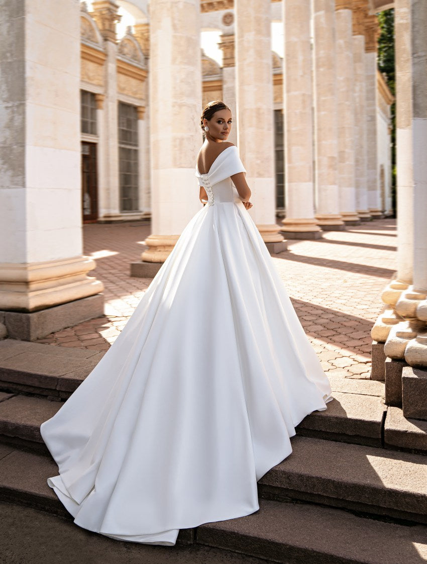Woman in a white wedding dress standing on steps with classical architecture in the background