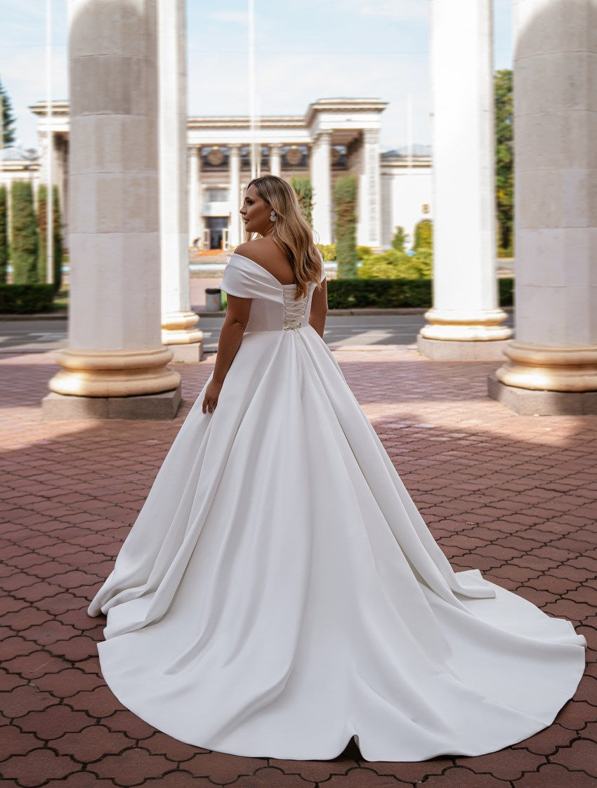 Woman in a white wedding dress standing in front of classical columns.