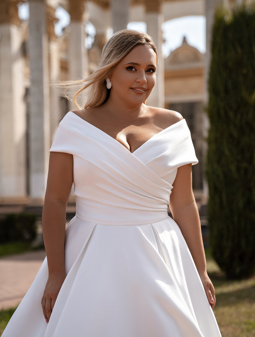 Woman wearing a white off-shoulder wedding dress outdoors.