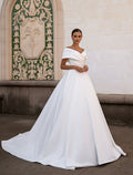 Woman in a white wedding dress standing in front of an ornate wall.