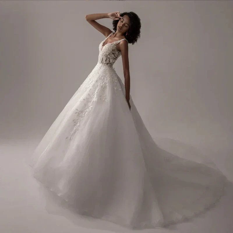 Woman wearing a white wedding dress with intricate detailing on a plain background