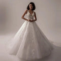Woman wearing a white wedding dress with intricate detailing on a neutral background