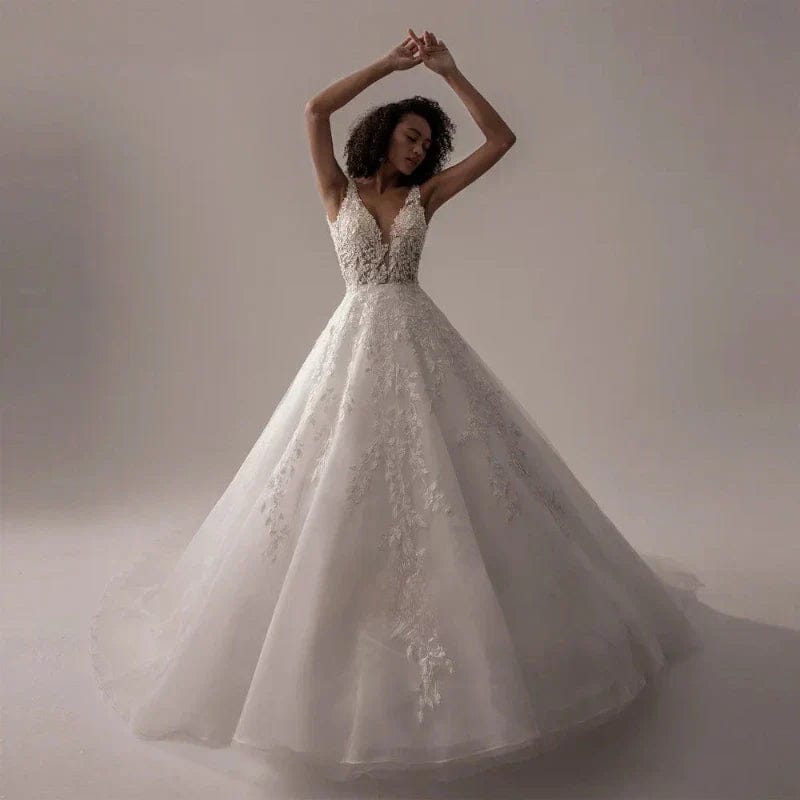 Woman in a white wedding dress with lace details against a neutral background